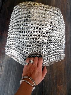 a woman's hand is holding onto a silver purse on top of a wooden table