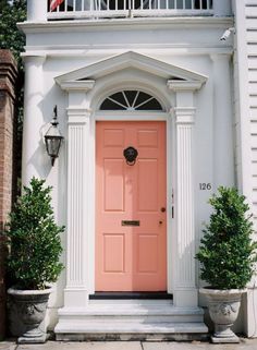 an orange front door on a white house