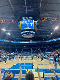 the inside of a basketball court with people on it and fans in the stands holding up their cell phones