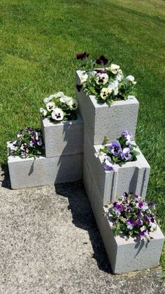 four cement planters with flowers growing out of them