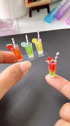 someone is holding small miniature cocktails in their hands and they are on the table