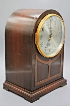 an antique wooden clock with roman numerals on the front and sides, sitting upright