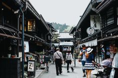 several people walking down an alley way with shops