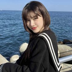 a young woman standing on top of a pier next to the ocean with her arms crossed