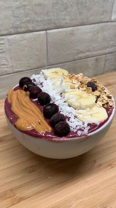 a bowl filled with fruit and nuts on top of a wooden table