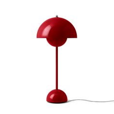 a red table lamp sitting on top of a white floor next to a light bulb