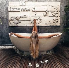 a woman laying in a bathtub with flowers on the floor