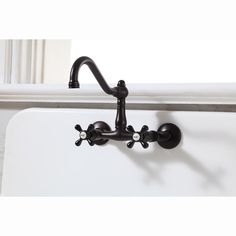 a black faucet on the side of a white sink with two spigots