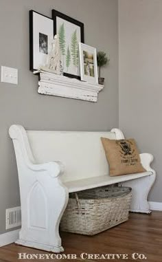 a white bench sitting on top of a hard wood floor next to a basket filled with flowers