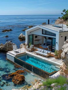 a house with a swimming pool in front of it next to the ocean and rocks