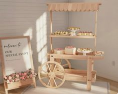 a wooden cart filled with cakes and pastries on top of a white rug next to a sign