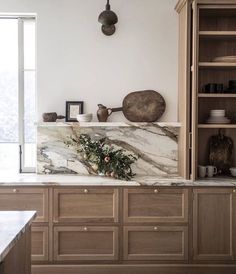 a kitchen with marble counter tops and wooden cabinets, along with pots on the wall