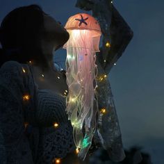 a woman standing in front of a jellyfish lamp