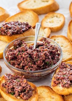 a bowl filled with food sitting on top of crackers next to some bread slices