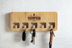 a wooden key holder with six keys hanging from it's hooks on a wall