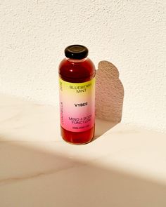 a bottle of vitamin oil sitting on top of a white counter next to a shadow