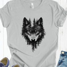 DESCRIPTION: This striking design combines the fierce presence of a wolf with the serene beauty of a forest, creating a powerful and captivating image. The wolf's intense gaze emerges from the trees, symbolizing strength, resilience, and the deep connection between nature and spirit. Wearing this t-shirt brings an untamed, wild essence to your style, perfect for those who embrace the call of the wilderness. Our most popular Bella+Canvas tee feels soft and light, with just the right amount of str Spirit Animal Wolf, Wolf Spirit Animal, Wolf Shirt, Wolf T Shirt, Grey Wolf, Bella Canvas Tees, Woodland Creatures, Prism Color, Ash Color