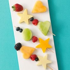 a white plate topped with fruit on top of a blue table next to strawberries and kiwis