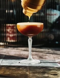 a glass filled with liquid sitting on top of a tiled floor next to a building