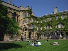 people sitting on the grass in front of an old building