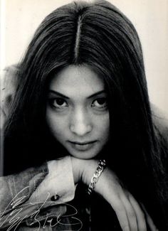 a black and white photo of a young woman with long hair, wearing a jacket