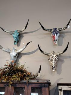 three steer heads mounted to the side of a wall next to a vase filled with flowers