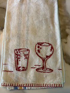 a towel with two glasses on it sitting on top of a counter next to a cup