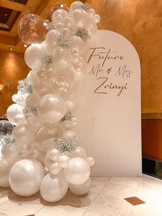 a tall white balloon column with silver and white balloons