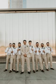 a group of men standing next to each other in front of a tall metal wall