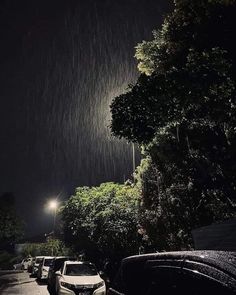 cars are parked on the side of the road at night in the rain with street lights