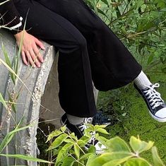 a man sitting on top of a cement bench next to green plants and bushes,