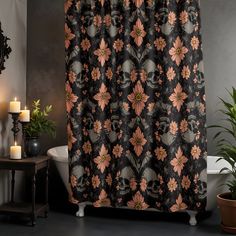 a bath tub sitting next to a shower curtain with skulls and flowers printed on it