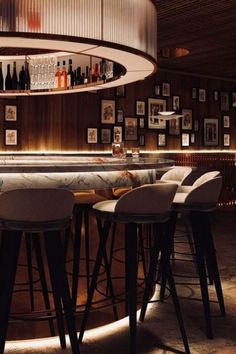 a dimly lit bar with stools and pictures on the wall in the backround