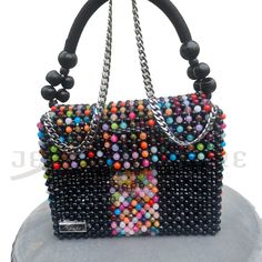 This one-of-a-kind, finely assembled, marble pattern bead by bead black and a multicolor bag is designed in a fold-over silhouette with two different straps (chain and wooden beaded nylon rope strap) and a magnetic snap that opens to reveal room for all your essentials. * Black and multicolor round beads * Marble pattern beads * Gold-tone hardware * Magnetic snap closure * Flap style * Unlined * Detachable straps * Shoulder length chain strap * Wooden beaded nylon rope strap * 8.5"W X 6"H X 3"D Luxury Handmade Multicolor Shoulder Bag, Black Beaded Square Shoulder Bag, Rectangular Bag With Black Beads As Fashion Accessory, Trendy Multicolor Beaded Shoulder Bag, Trendy Multicolor Beaded Bags, Trendy Multicolor Shoulder Bag For Evening, Multicolor Rectangular Shoulder Bag With Colorful Beads, Black Beaded Rectangular Shoulder Bag, Black Beaded Bags As Fashion Accessory