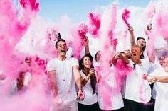 a group of people standing next to each other with pink powder on their faces and hands