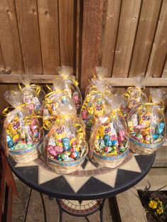 several baskets filled with candy sitting on top of a table next to a wooden fence