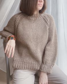 a woman sitting in a chair wearing a sweater