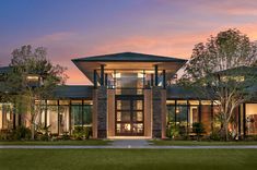 an architectural rendering of a modern house at dusk with trees and grass in the foreground