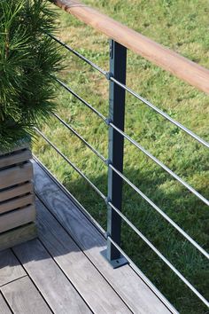 a potted plant sitting on top of a wooden deck next to a metal railing