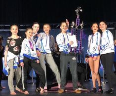 a group of young people standing next to each other on a stage with trophies in their hands