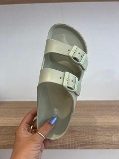 a person is holding up a pair of sandals