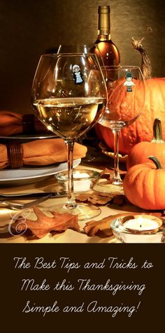 two wine glasses sitting on top of a table next to pumpkins and other items