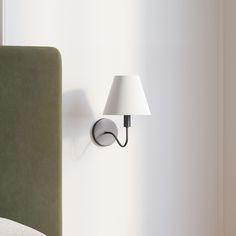 a lamp is on the wall next to a bed