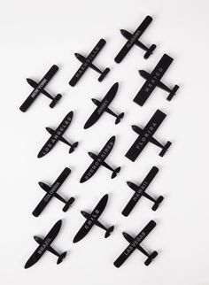 a bunch of small black planes sitting next to each other on a white table top