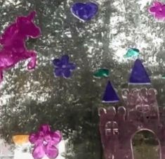 the window is decorated with purple and green glass pieces, which are shaped like castles