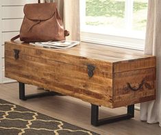 a wooden bench with a purse on top of it next to a rug and window