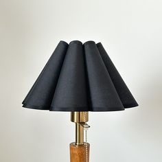 a wooden table lamp with black lampshades on it and a white wall in the background