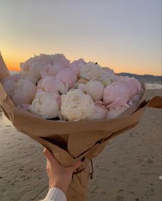 a person holding a bouquet of flowers on the beach