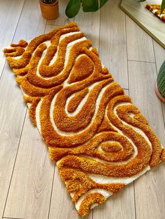 an orange and white rug on the floor next to some potted plants in front of a mirror