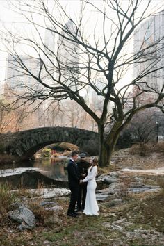 a bride and groom standing in front of a bridge